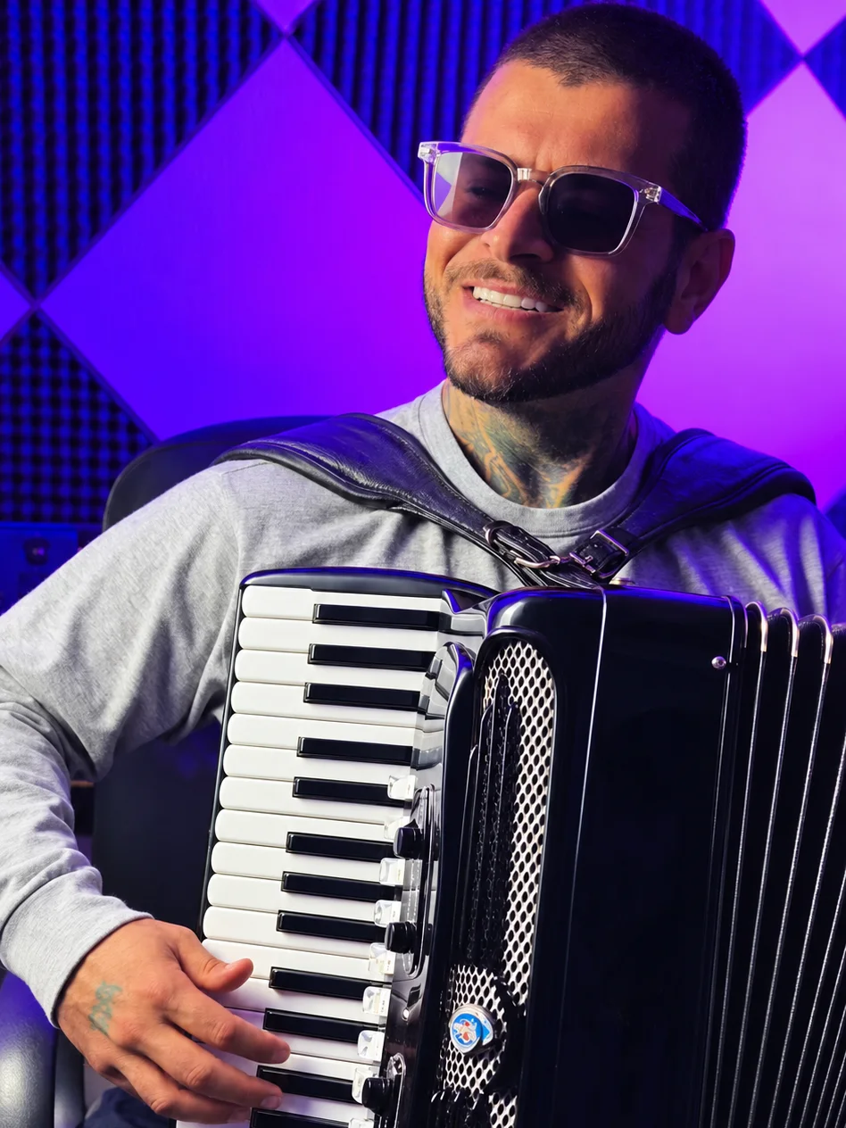 Clayton Gama sorrindo com a sanfona, sob luz roxa
